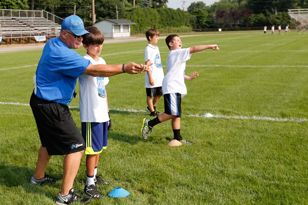 SPT-lionscamp22pCamp-director-and-coach-Jim-Hamilton-works-with-Kaden-H-on-passing-the-football