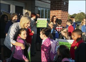Second grade teacher Kim Downour, left, gives a hug to one of her students, Madison Mullins, at Oakdale Elementary School with other members of the Toledo Federation of Teachers in October. Toledo's Board of Education votes today on a 3-year contract with its teachers union.