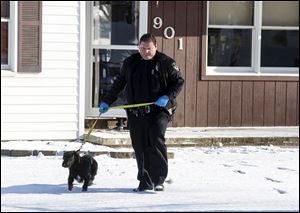 A member of the Delta Police Department leads a dog out of a home in the 900 block of Fernwood after investigating the scene of the shooting of Amanda Mangas, 23.