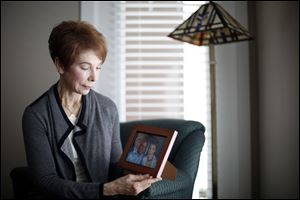 Linda Hanna, whose husband Hal died of ALS earlier this year, sits in her living room and looks at a portrait of she and her husband in Bowling Green on March 16, 2017.