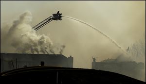 Firefighters fight an eight-alarm fire that began at an apartment complex under construction and than spread to several nearby homes Monday in Overland Park, Kan. 
