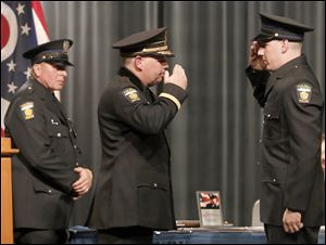 Toledo Police Chief George Kral salutes his son George R. Kral III after handing him his badge during the 63rd Toledo Police Academy graduation ceremony at Bowsher High School.