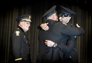 Detective Norm Cairl hugs his son Zachary Cairl after presenting him his badge during the 63rd Toledo Police Academy graduation ceremony at Bowsher High School Friday. 