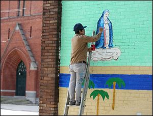 Artist David Cuatlacuatl paints a figure representing the Immaculate Conception on a mural at The Immaculate Conception Church outreach center June 7.  Mr. Cuatlacuatl was killed in a head-on crash on Thursday.