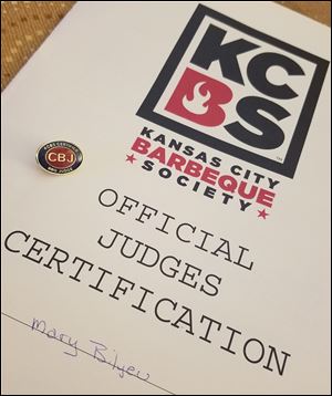 The official KCBS class manual and Certified Barbeque Judge pin. 