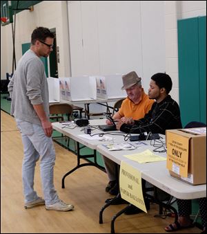 David Padgett of Toledo, left, signs in to vote with poll workers Dennis Stasiak, center, and William Hughes, both of Toledo, at Old Orchard Elementary School. The voting is going 'slow, but steady' at the school in Toledo on Tuesday.