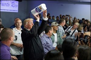President Donald Trump tosses paper towels into a crowd as he hands out supplies at Calvary Chapel in Guaynabo, Puerto Rico. 