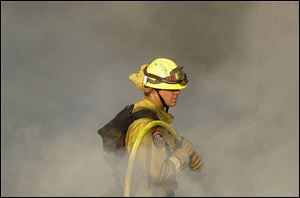 A Cal Fire firefighter works on hot spots on a hill in the Oakmont area of Santa Rosa, Calif.