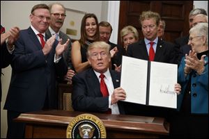President Donald Trump shows an executive order on health care that he signed in the Roosevelt Room of the White House on Thursday.