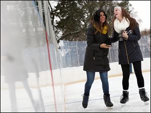 Felicia Christopher, left, and Allison Morrison, right, laugh together as they skate across the ice January 13 at the Ottawa Park Ice Rink in West Toledo.