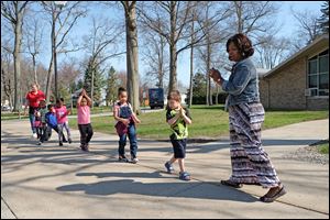 Eisha Hearn, sings a song with the children as she leads them from the bus back to their classroom in April of 2016. A recently released research paper criticizes the methodology used for Ohio's school report cards.