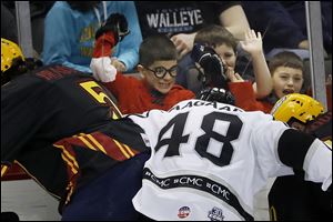 Young fans decked out in wizard gear for Harry Potter Night at the Huntington Center cheer on Austin Brassard (5) of the Toledo Walleye as he battles Manchester's Mikkel Aagaard for the puck.