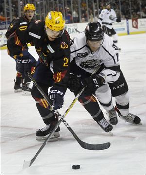Mike Borkowski of the Toledo Walleye and Zac Lynch of the Manchester Monarchs in pursuit of the puck during Saturday's game. The Walleye have started donning yellow helmets for select games this season.