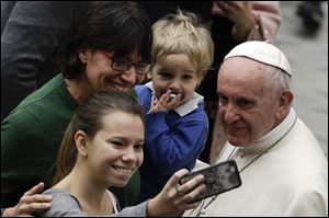 Pope Francis poses for a family picture as he greets faithful during the weekly general audience at the Vatican Jan. 10. 