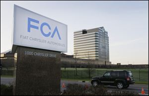 A vehicle moves past a sign outside Fiat Chrysler Automobiles world headquarters in Auburn Hills, Mich.