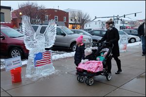 Emery Hudson, 6, left, answers her mother, Meg Hudson, who asks her to identify an ice-sculpted bird at Perrysburg Winterfest. in the carriage are Hadley, 4, and Quinn, 2. 