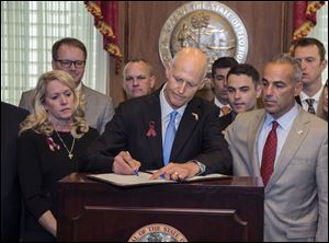 Florida Gov. Rick Scott signs the Marjory Stoneman Douglas Public Safety Act in the governor’s office in Tallahassee, Fla.