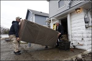 Thomas Gonzales, left, helps his neighbor Dale Jessick, right, remove damaged furniture from his home that was flooded on Allen Cove Road in Luna Pier, Mich., on Monday.