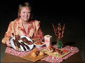 Kris Ruedy, President of the Toledo Hungarian Club, with an assortment of food for the Beer and Bacon Festival Saturday at the Toledo Hungarian Club in Toledo. The food includes bacon toffee, chocolate covered bacon, pretzels rolled in bacon, pogacsa, bacon & beer macaroni & cheese, bacon-infused popcorn, honkey turkey, and a Birmingham hot dog.