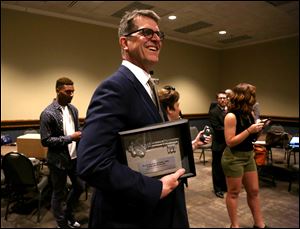 Jim Harbaugh holds the key to the city presented to him by the mayor ahead of the ABLE Access to Justice awards dinner.