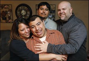 Jenny Hughes, left, her sons Gabe, 23, front center, Jay Castro, 24, top center, and husband Shawn Hughes embrace as they stand in their living room Friday, May 11, 2018, in Walbridge. Both Gabe and Jay are on the autism spectrum and are mostly nonverbal.