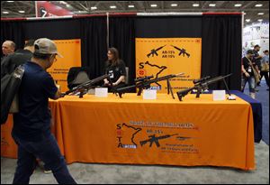 Attendees walk by a display of AR-15's and AR-10's at the National Rifle Association convention in Dallas. 
