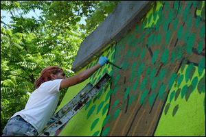 BGSU art student Paul Verdell, of Perrysburg, painting the East Broadway mural. Students in the Art Department of Bowling Green State University paint a mural on East Broadway in east Toledo on Thursday.