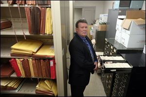 Jay Gast stands in the  stacks of cold case records in the basement of the TPD Safety Building.