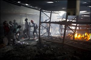People loot a Delimart store that was burned during two days of protests against a planned hike in fuel prices in Port-au-Prince, Haiti, Sunday, July 8, 2018. 