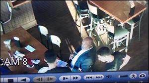 A security camera still shows Toledo Councilman Tyrone Riley speaking with business owners Mohamed and Akram Mamoud at Andy’s Sports Bar and Jojo’s Pizza, located at 4941 Dorr St. in Toledo.
