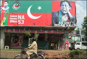 A Pakistani motorcyclist rides past a billboard featuring an image of Imran Khan, head of the Pakistan Movement for Justice party, a day after the general election in Islamabad on July 26.