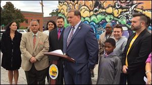Mayor Wade Kapszukiewicz, center, and other city officials gather at Toledo's 'love wall' on Adams Street to celebrate Toledo's scoring 103 points out of 100 on the Human Rights Campaign’s Municipal Equality Index for 2018.