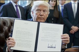 President Trump shows off his signature on an executive order about the Dakota Access pipeline in the Oval Office of the White House in Washington.